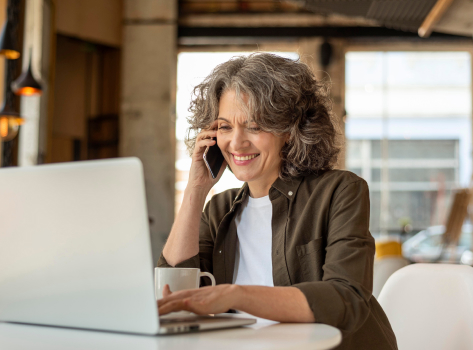 A woman using her computer while talking on the phone