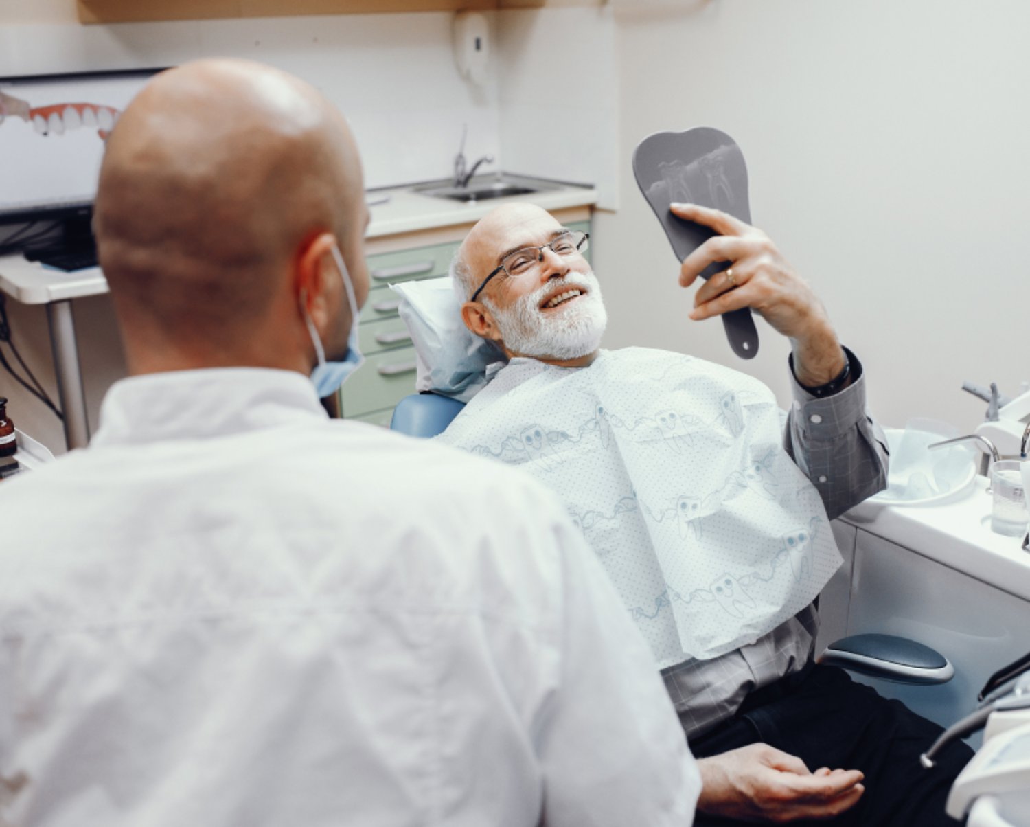 A man smiling and looking into a mirror in the office